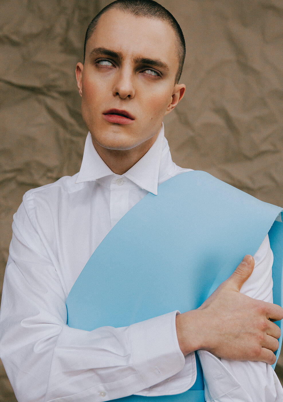 An editorial image of man posing in the studio wearing designer clothing and rolling his eyes