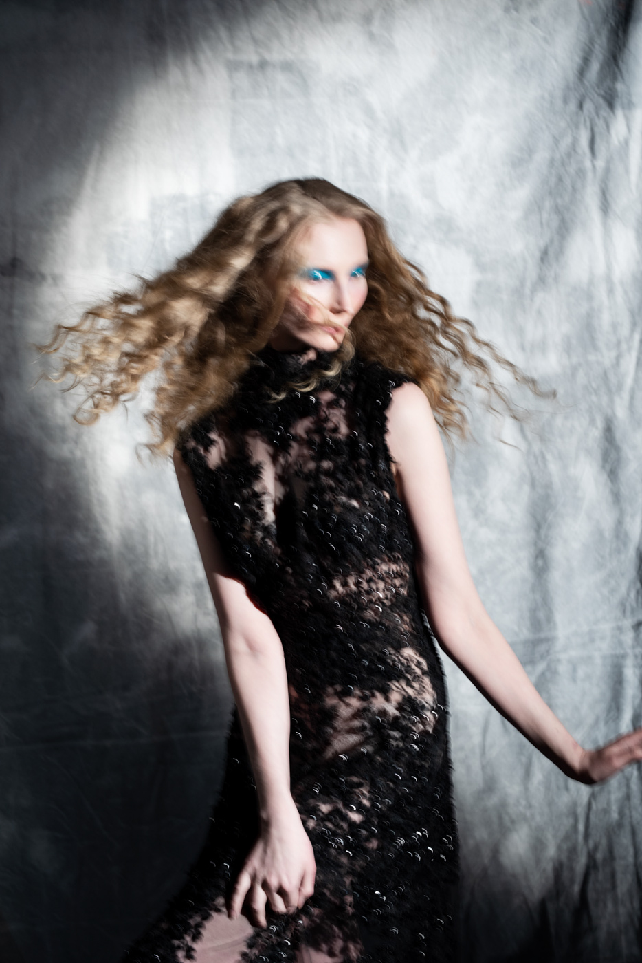Dramatic_fashion_editorial_portrait_of_woman_with_curly_hair_wearing_black_lace_dress_on_grey_background_photographed_by_Sara_Lehtomaa