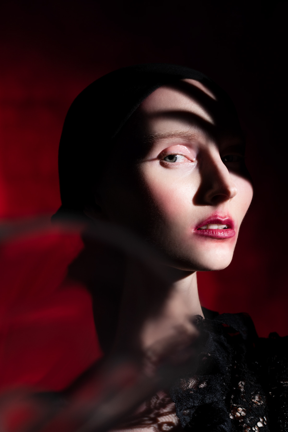 Dramatic_distorted_dreamy_beauty_editorial_portrait_of_woman_with_red_lips_wearing_black_lace_on_red_background_photographed_by_Sara_Lehtomaa
