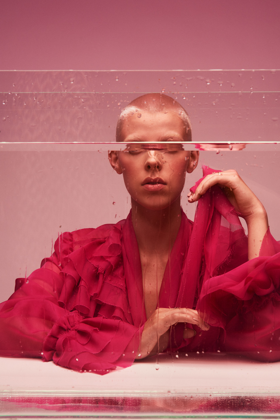 Short_haired_blond_woman_wearing_pink_behind_aquarium_on_pink_background_photographed_by_Sara_Lehtomaa