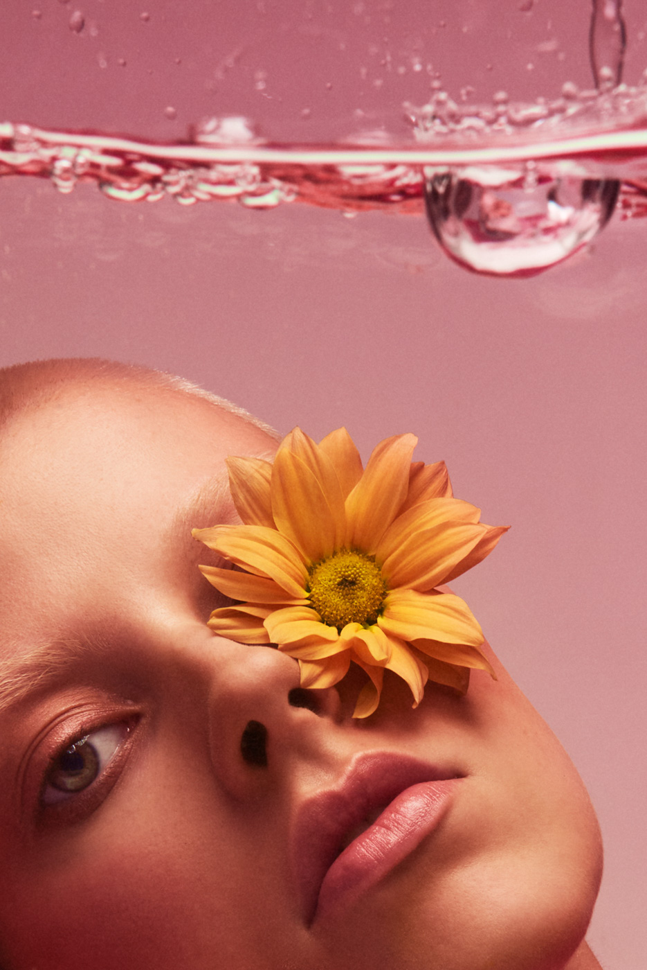 Short_haired_blond_woman_with_yellow_flower_under_water_on_pink_background_photographed_by_Sara_Lehtomaa