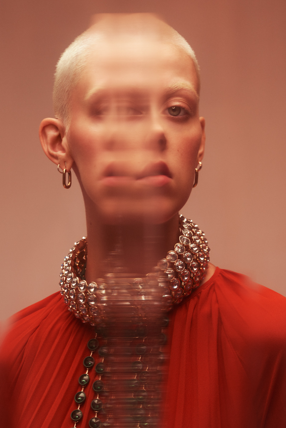 Distorted_face_of_short_haired_blond_woman_wearing_diamond_choker_on_orange_background_photographed_by_Sara_Lehtomaa