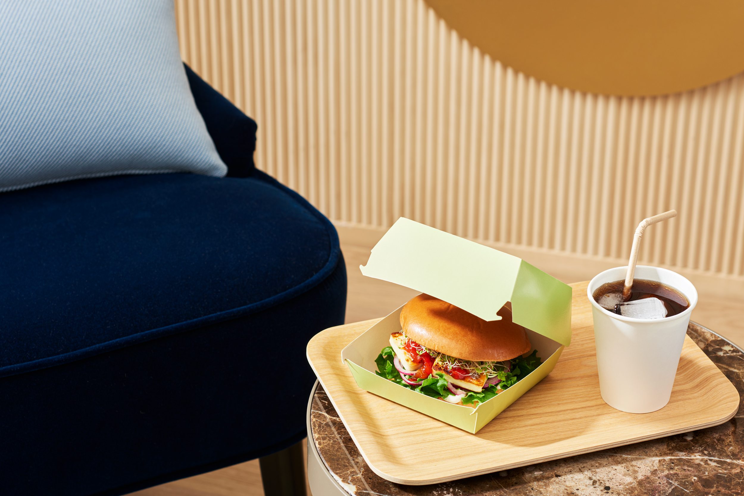 A_hamburger_and_a_soft_drink_on_a_wooden_tray_using_Stora_Ensos's_packaging_materials_by_Elina_Himanen
