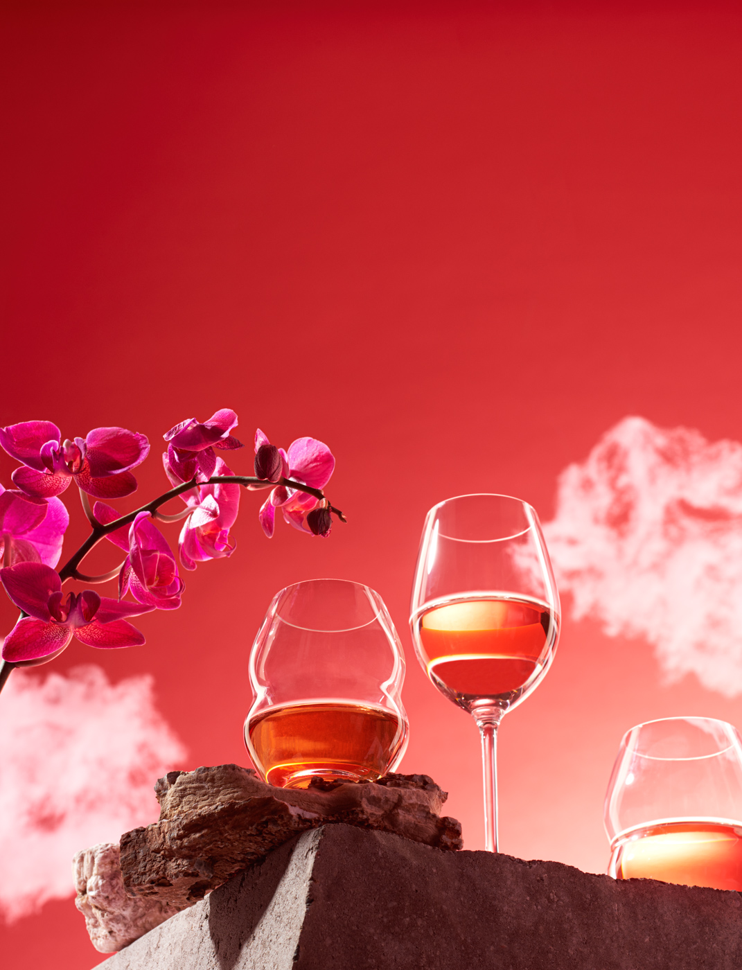 three_rose_wine_glasses_on_a_cliff_and_red_cloudy_sky_with_fuchsia_Orchidea_flower_by_Elina_Himanen