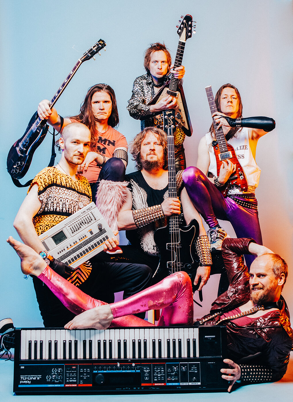 A colorfull image of a band posing in the studio with instruments