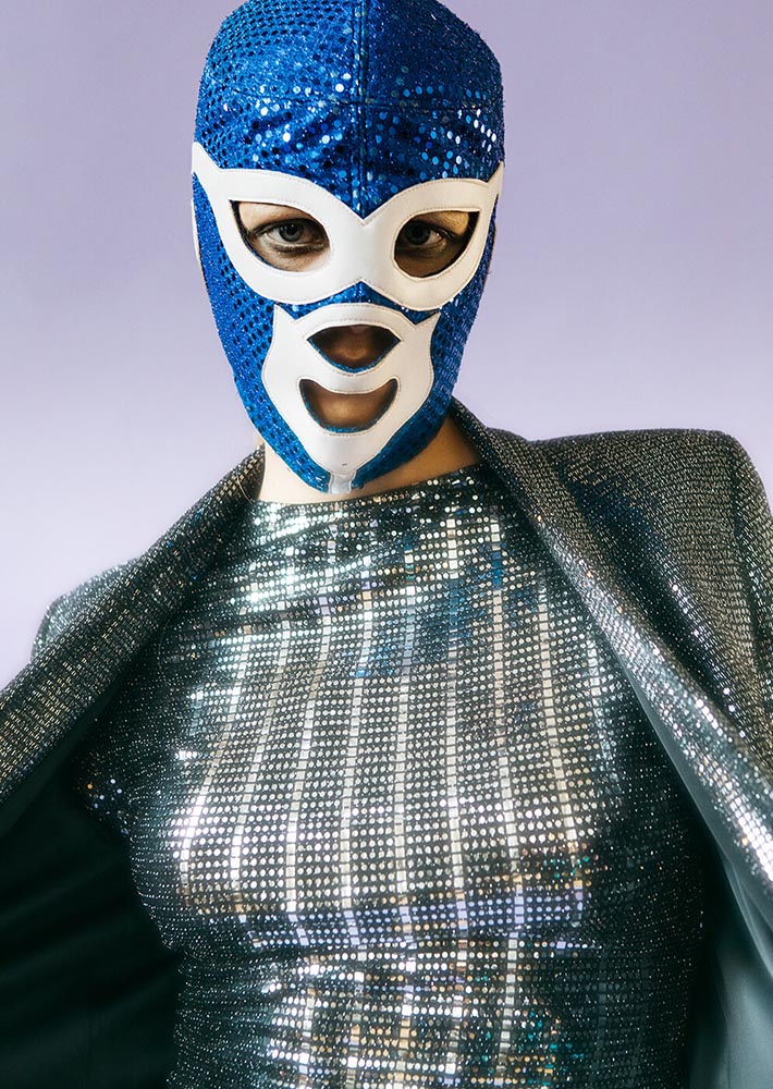 An editorial picture of girl wearing shiny clothing and a Mexican wrestling mask