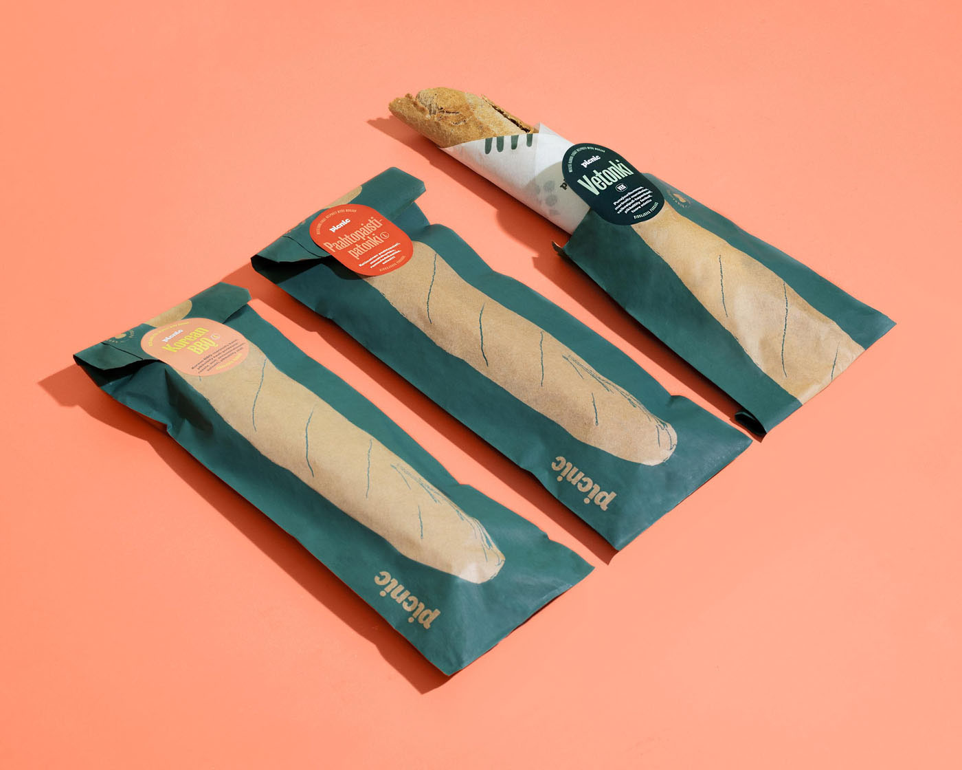 three baguette packages laying in a row with one baguette sticking out of a package on a pink background by Tomas Olsen